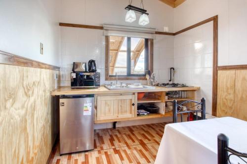 a kitchen with a stainless steel refrigerator and a counter at Cabañas Natales Rotundo in Puerto Natales