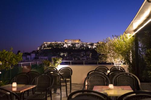 a patio with tables and chairs with the view of the acropolis at Attalos Hotel in Athens