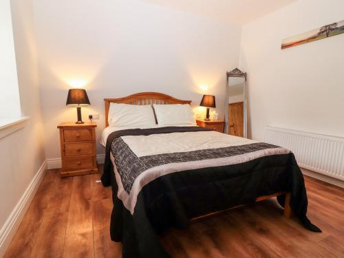 a bedroom with a bed and two night stands with lamps at Laharn Cottage in Killorglin