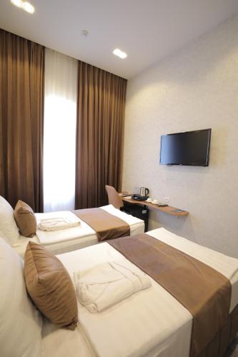 a hotel room with four beds and a flat screen tv at MaxWell Hotel & SPA in Tashkent