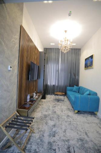 a living room with a blue couch and a chandelier at MaxWell Hotel & SPA in Tashkent