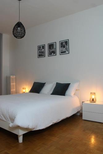 a bedroom with a white bed with three pictures on the wall at Appartamento Perini in Trento