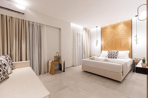 a white bedroom with a bed and a couch at Senso Deluxe in Limenaria