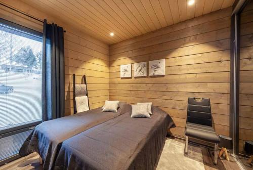 a bedroom with a bed and a chair in it at Chalet Ellivuori huoneisto as 1 in Sastamala