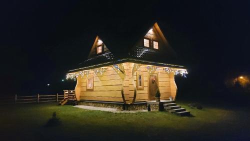 a large wooden house with lights on it at night at Słoneczna Chata z Bali in Lądek-Zdrój