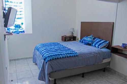 a bedroom with a bed with a blue blanket at Hotel y Café Ixmati Suchitoto in Suchitoto