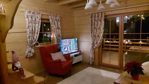 a living room with a red chair and a television at Słoneczna Chata z Bali in Lądek-Zdrój