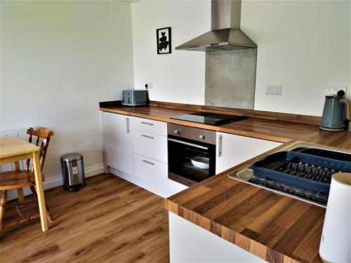 a kitchen with white cabinets and a wooden counter top at The Garden Room - Nature Stay in Suckley