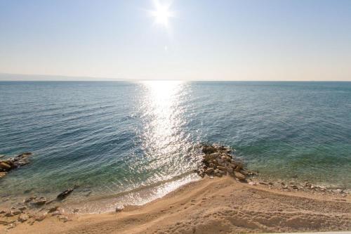 a beach with the sun reflecting on the water at Villa Tamaris on the beach in Podstrana