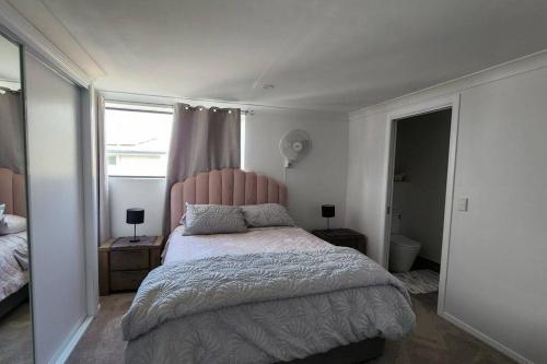 a bedroom with a bed with a pink headboard and a window at Oscar's at Banora in Kurrara