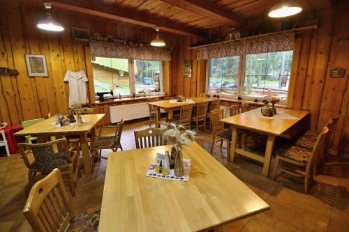 a restaurant with wooden tables and chairs and windows at Apartmány Jakub in Belá