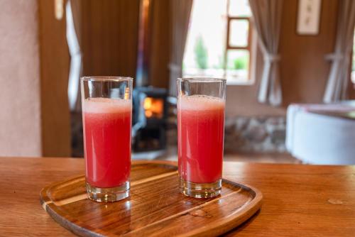 two glasses of red juice sitting on a wooden tray at Unuwasi Hotel & Villa in Calca