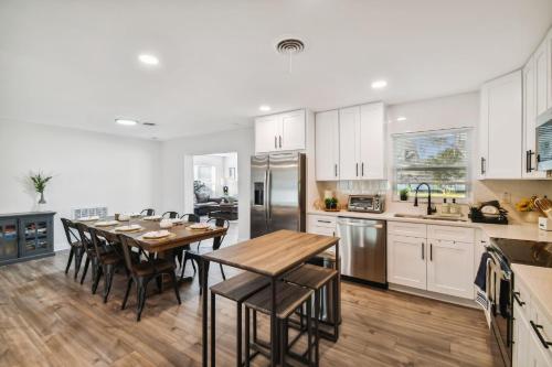 a kitchen with white cabinets and a wooden table and chairs at Plush sheets, Games!, Huge backyard, Massage Chair in Tampa