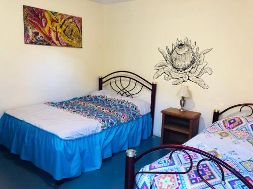 a bedroom with two beds and a painting on the wall at Los Nardos Hostel -pet friendly- in Oaxaca City