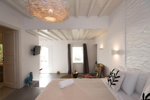 a white bedroom with a bed and a living room at Bellou Suites in Mýkonos City