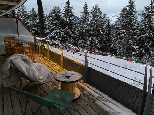 a table and chairs on a deck with christmas lights at Mélèze B *** plein Sud in Chamrousse