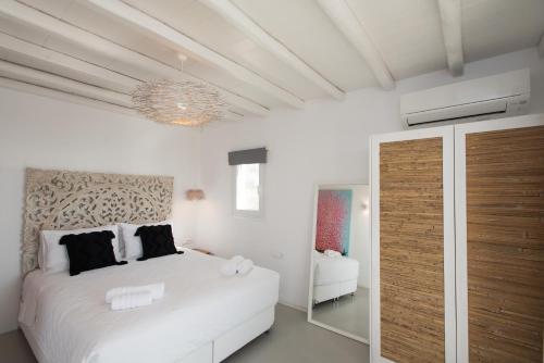 a white bedroom with a bed and a chandelier at Bellou Suites in Mýkonos City