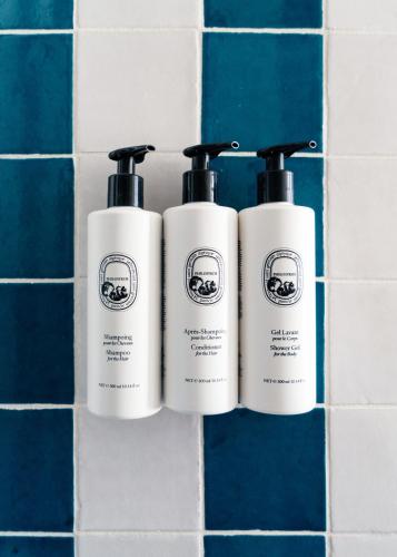 a trio of three shampoo bottles on a tiled wall at Palihotel San Diego Gaslamp Quarter in San Diego