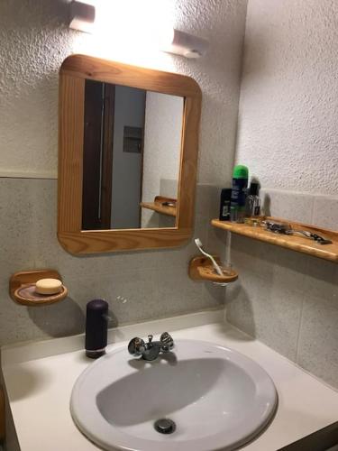 une salle de bain avec un lavabo blanc et un miroir dans l'établissement Barèges Appartement vue montagne, à Barèges