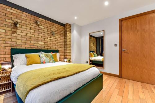 a bedroom with a large bed and a brick wall at Spacious 2 Bed Urban Jungle Flat, Central London in London