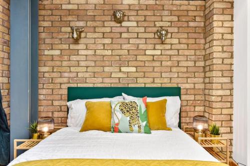 1 dormitorio con 1 cama con pared de ladrillo en Spacious 2 Bed Urban Jungle Flat, Central London, en Londres