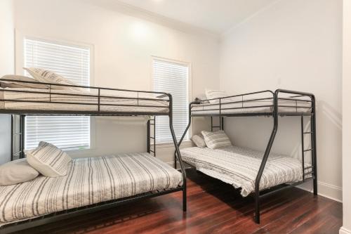 two bunk beds in a room with two windows at Canal Street Mini Mansion Sleeps 15 in New Orleans