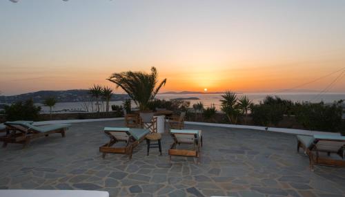 a patio with chairs and a table at sunset at Bellou Suites in Mýkonos City