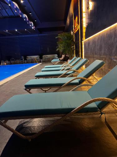 a row of blue lounge chairs next to a pool at MaxWell Hotel & SPA in Tashkent