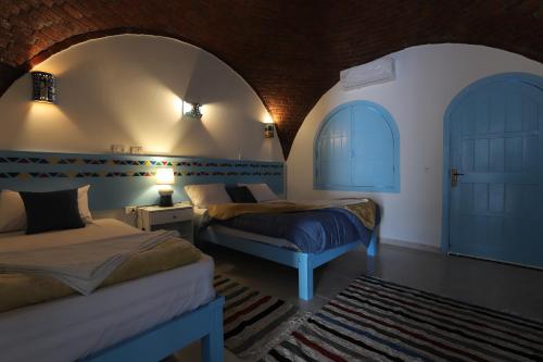 a bedroom with two beds and two arched windows at Noprea Boutique Hotel in Aswan