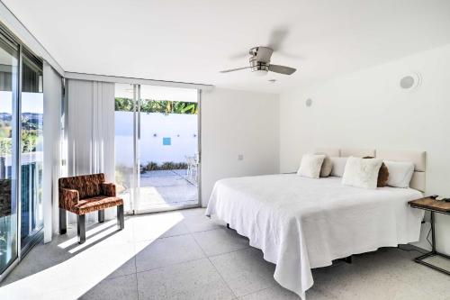 - une chambre blanche avec un lit et une chaise dans l'établissement Palm Springs Home in Seven Lakes Country Club, à Palm Springs