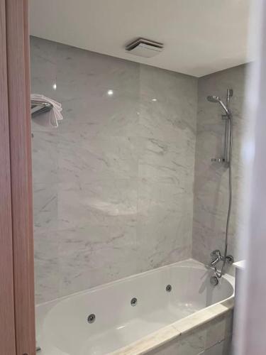 a white bathroom with a tub and a shower at Superbe appartement avec piscine in Rabat