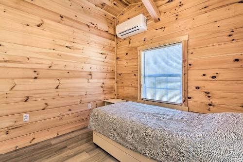 a bedroom with a bed and a window in a wooden wall at Laurelville Cabin Less Than 11 Mi to Old Mans Cave! in Laurelville