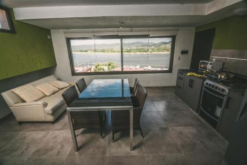 a living room with a table and a couch and a kitchen at lacasonavistalago in Villa Carlos Paz
