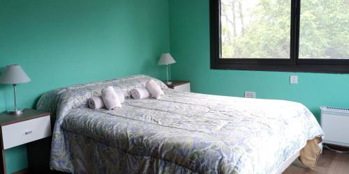 Un dormitorio con una cama con paredes azules y una ventana en La Eugenia en Sierra de los Padres