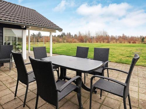 a table and chairs on a patio with a field at 14 person holiday home in H jslev in Sundstrup