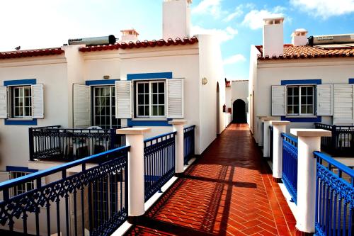 a walkway between two white houses with blue gates at Patios da Vila - Duna Parque Group in Vila Nova de Milfontes