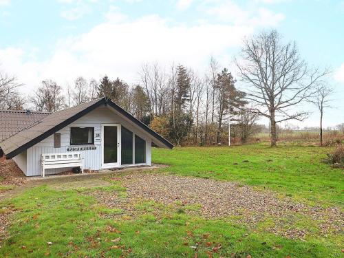 a small white house with a bench in a field at 6 person holiday home in Roslev in Vester Grønning