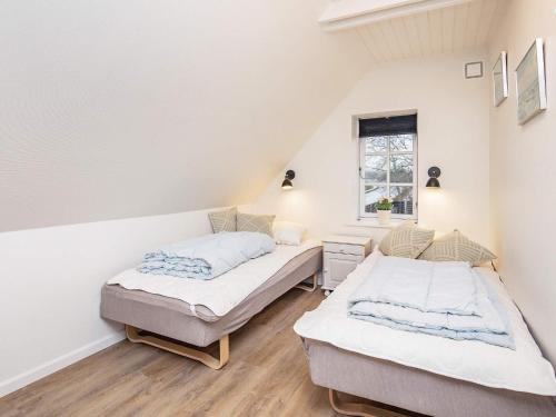 two beds in a room with white walls and wooden floors at 10 person holiday home in Roslev-By Traum in Roslev