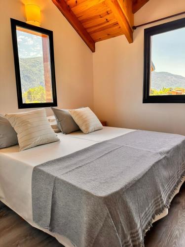 a large bed in a room with two windows at Complejo Camino al Lago in Lago Puelo