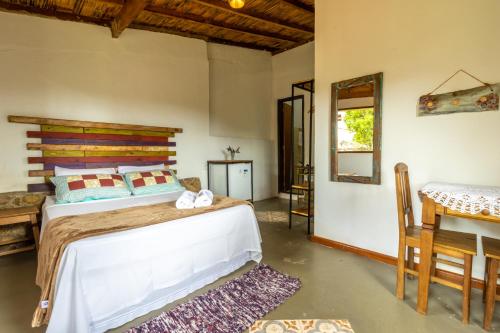 a bedroom with a bed and a table and a desk at Pousada Casa do Geninho in Conceição da Ibitipoca