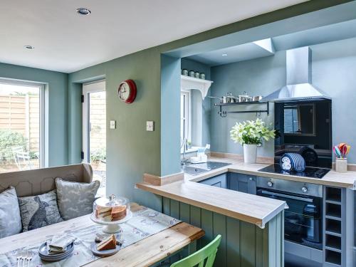 a kitchen with green walls and a wooden table at Rose Cottage in North Elmham