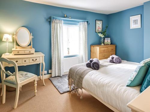 a blue bedroom with a bed and a mirror at Rose Cottage in North Elmham
