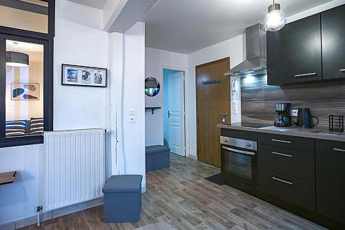 une cuisine avec des placards noirs et un tabouret bleu dans l'établissement Le Cosy Pasteur 5 min Hypercentre Parking public gratuit à proximité, à Troyes