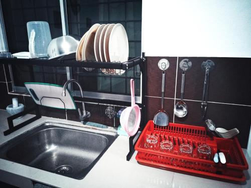 a kitchen with a sink and a red dish drying rack at VIRTA Guesthouse in Sandakan