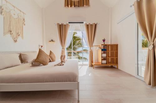 a white bedroom with a bed and a window at Sunset Lover Beach Residence in Thongsala