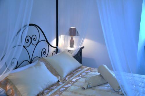 a bed with a black and white headboard and pillows at Masseria Rosa Trulli Relais in Alberobello