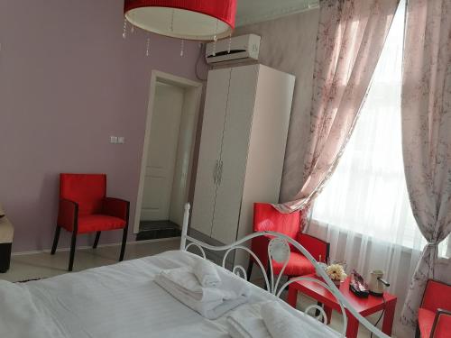 a bedroom with a bed and two red chairs at Citalna Rooms in Bitola