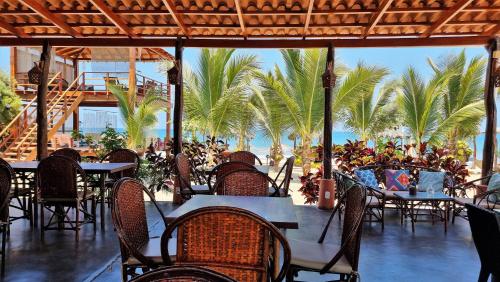 un restaurante con mesas, sillas y palmeras en Punta del Norte Bungalows, en Canoas de Punta Sal