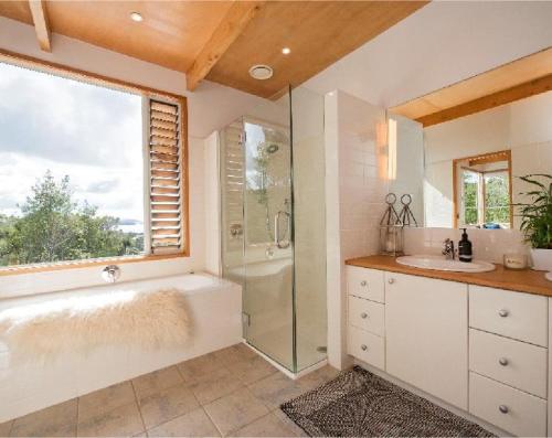 a bathroom with a tub and a shower and a sink at Private Luxury in Paihia - with Heated Pool! in Paihia
