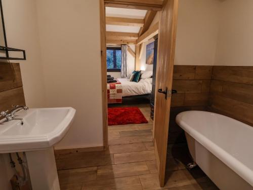 a bathroom with a sink and a tub and a bed at Lady Bagots Cabin in Ruthin